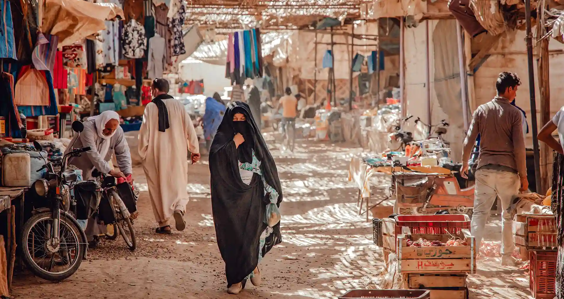 Woman wearing izar along black scarf in Moroccan souk in Rissani