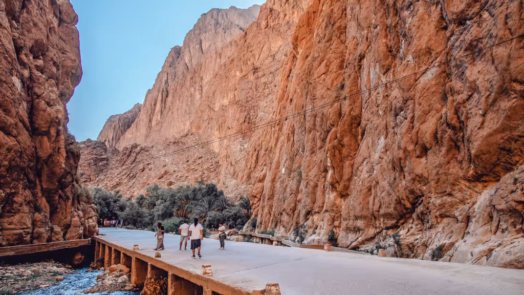 Travellers walking the road through Todra Gorge between red canyon walls on the Marrakech to Fes desert tour